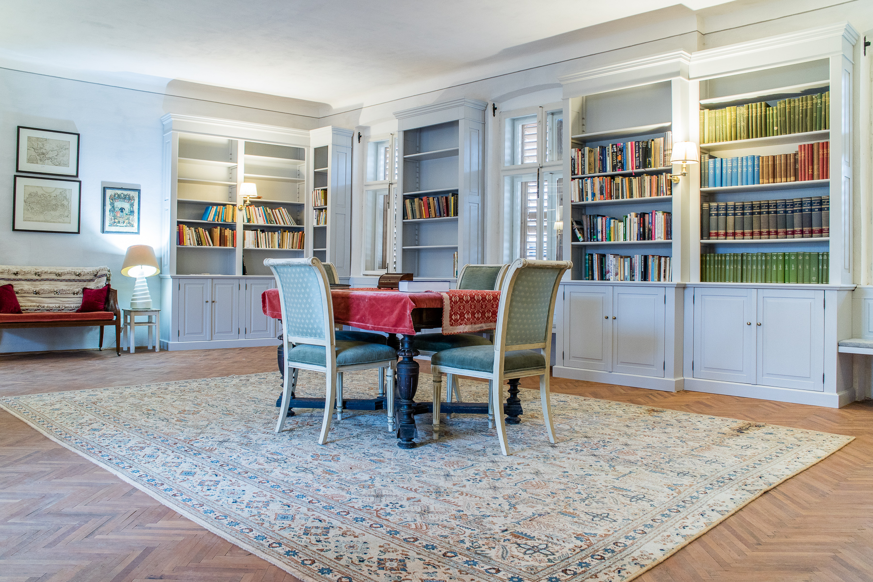 Biblioteca conacului din Richiș, cu rafturi pline de cărți și o masă veche în mijloc